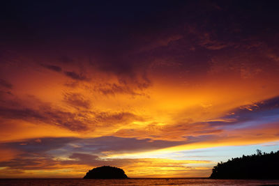 Scenic view of dramatic sky over silhouette trees during sunset