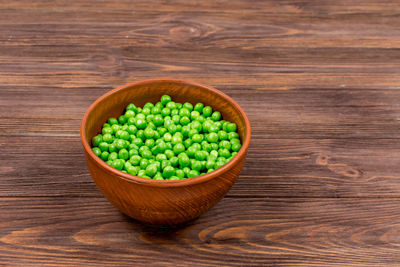 Fresh green peas in a bowl on a brown wooden table. place for an inscription.