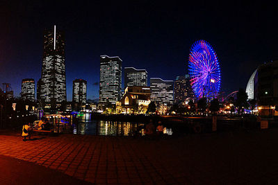 Illuminated ferris wheel in city at night