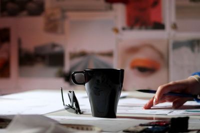 Cropped image of person hand by coffee cup on table