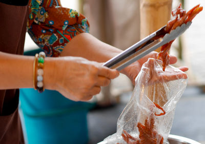 Cropped hands of woman packing fish in plastic bag