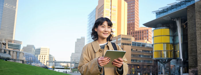 Young woman using mobile phone while standing in city