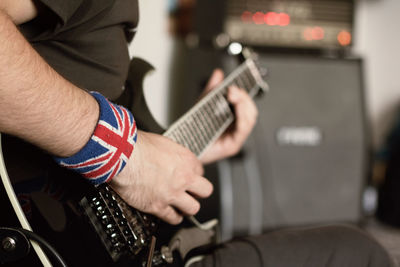 Midsection of male guitarist playing electric guitar at recording studio