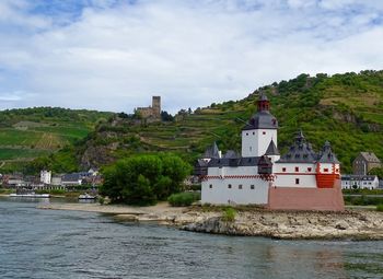 Buildings at waterfront on the rhine valley in germany against cloudy sky