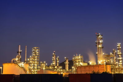 Illuminated factory against sky at night