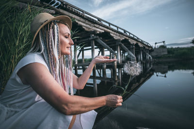 Girl with colored braids holds fluff on her hand, lightness