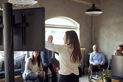 Businesswoman explaining to colleagues during meeting at creative office