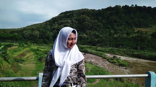 Smiling woman standing by railing