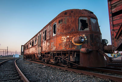 Abandoned train on railroad track against clear sky