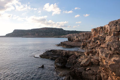 Rock formations by sea against sky