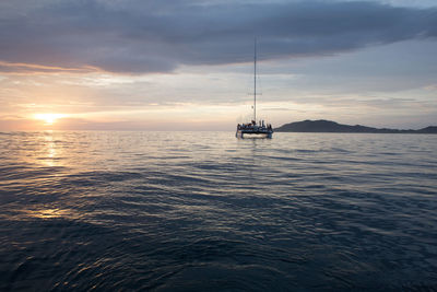 Sailboat sailing in sea at sunset