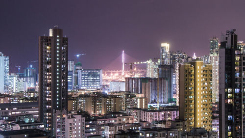 Illuminated buildings in city against sky at night