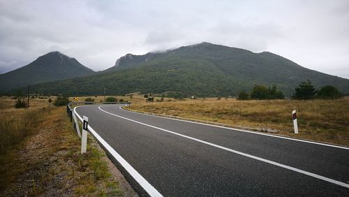 Road leading towards mountains against sky