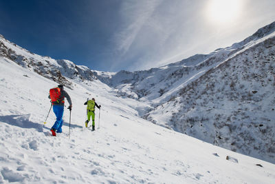 People on snowcapped mountain against sky