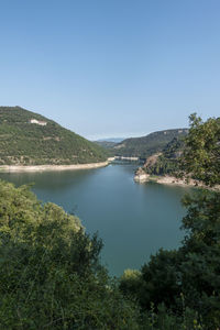 Scenic view of lake and mountains against clear blue sky