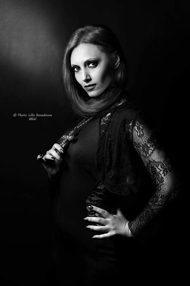 PORTRAIT OF YOUNG WOMAN WITH HAIR OVER BLACK BACKGROUND