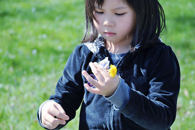 Close-up of girl holding flowers on field