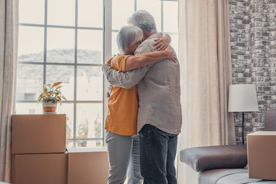 Rear view of woman standing by window at home
