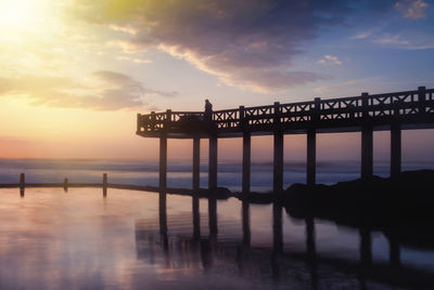 Silhouette pier over sea against sky during sunset