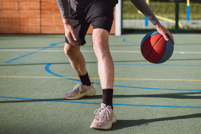 Boy practices dribbling basketball under his feet and improves his hand, body and foot coordination