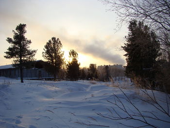 Snow covered field against sky during sunset