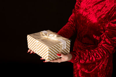 Midsection of person holding paper against black background