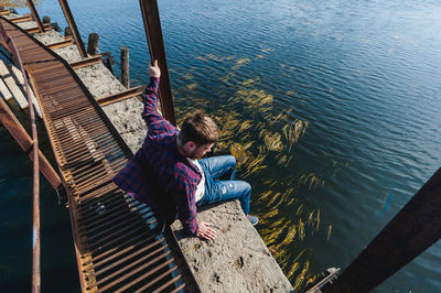 High angle view of woman sitting on wood by sea