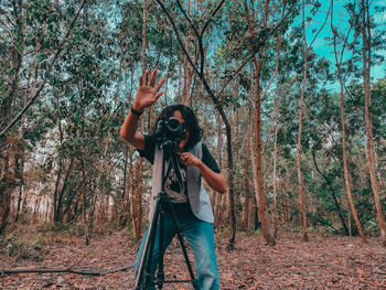 Man standing by tree in forest