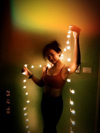 Young woman standing against illuminated lights