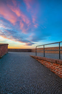 Footpath by sea against sky during sunset