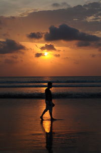 Silhouette man on beach against sky during sunset