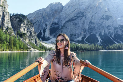 Smiling woman rowing boat in lake against mountains