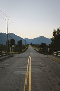 Road leading towards mountain against clear sky