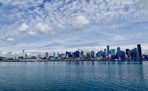 Sea by city buildings against sky