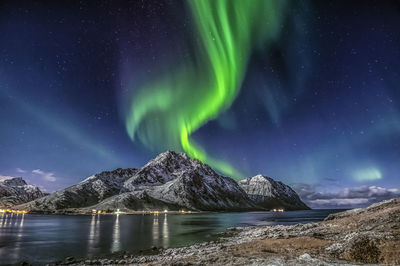 Scenic view of the northern lights and snowcapped mountains against sky at night