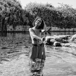 Woman standing by lake against trees