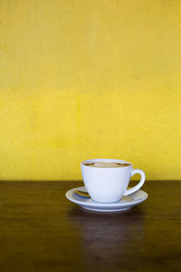 Close-up of coffee cup on table against wall