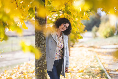 Portrait of young woman standing against trees