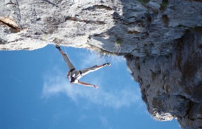 Directly below shot of women climbing wall against sky
