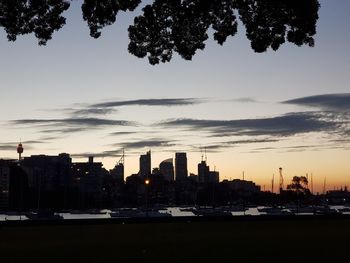 Silhouette buildings by city against sky during sunset