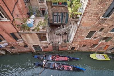 Boats moored in canal amidst buildings