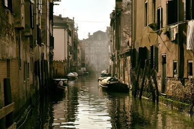 Boats in canal amidst buildings in city