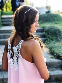 Rear view of woman with arms raised standing outdoors