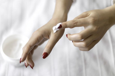 Beautiful groomed woman's hands with cream jar on the blanket. moisturizing cream for soft skin