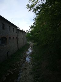 Empty footpath amidst buildings against sky