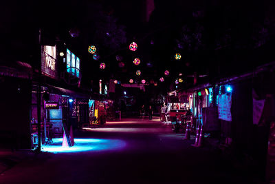 Illuminated street amidst buildings in city at night