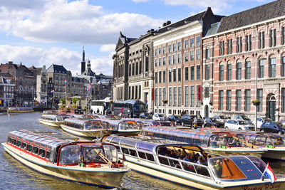 Boats moored in canal by buildings in city against sky