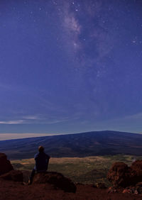 Rear view of man on landscape against sky at night