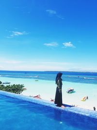 Rear view of woman swimming in sea against blue sky