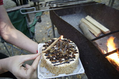 Cropped image of hands burning candles on birthday cake